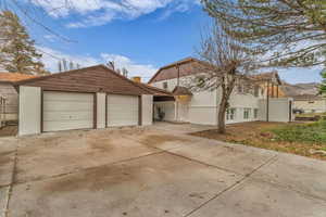 View of front of house with driveway, a garage, an outdoor structure, and stucco siding