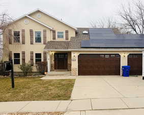 View of front of property featuring roof with shingles, stucco siding, concrete driveway, and a front yard