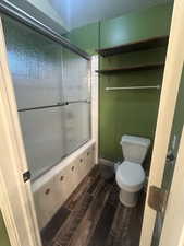 Full bathroom featuring wood finish floors and combined bath / shower with glass door