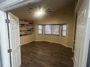 Primary bedroom with double doors, bay window, and ceiling fan