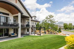 View of green lawn with stairway, a balcony, a patio, and a mountain view