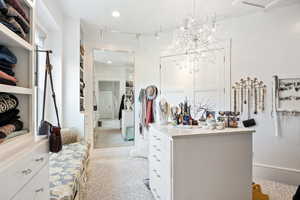 Walk in closet with light carpet and a chandelier