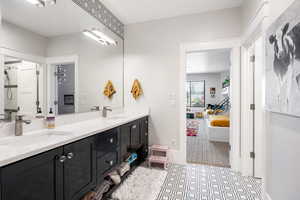 Ensuite bathroom with double vanity, a shower, and light flooring