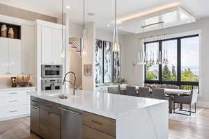 Kitchen with modern cabinets, white cabinets, decorative light fixtures, light wood finished floors, and recessed lighting