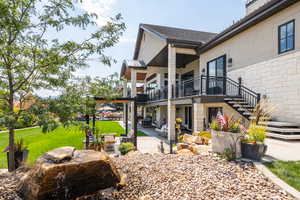 Rear view of house with a patio area, an outdoor living space, a balcony, stairway, and a lawn