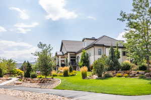 View of front facade with a front yard, stucco siding, and stone siding