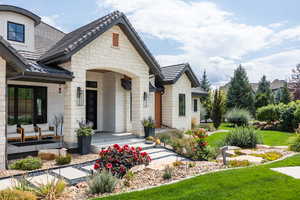 Property entrance with stone siding, a lawn, and a tile roof