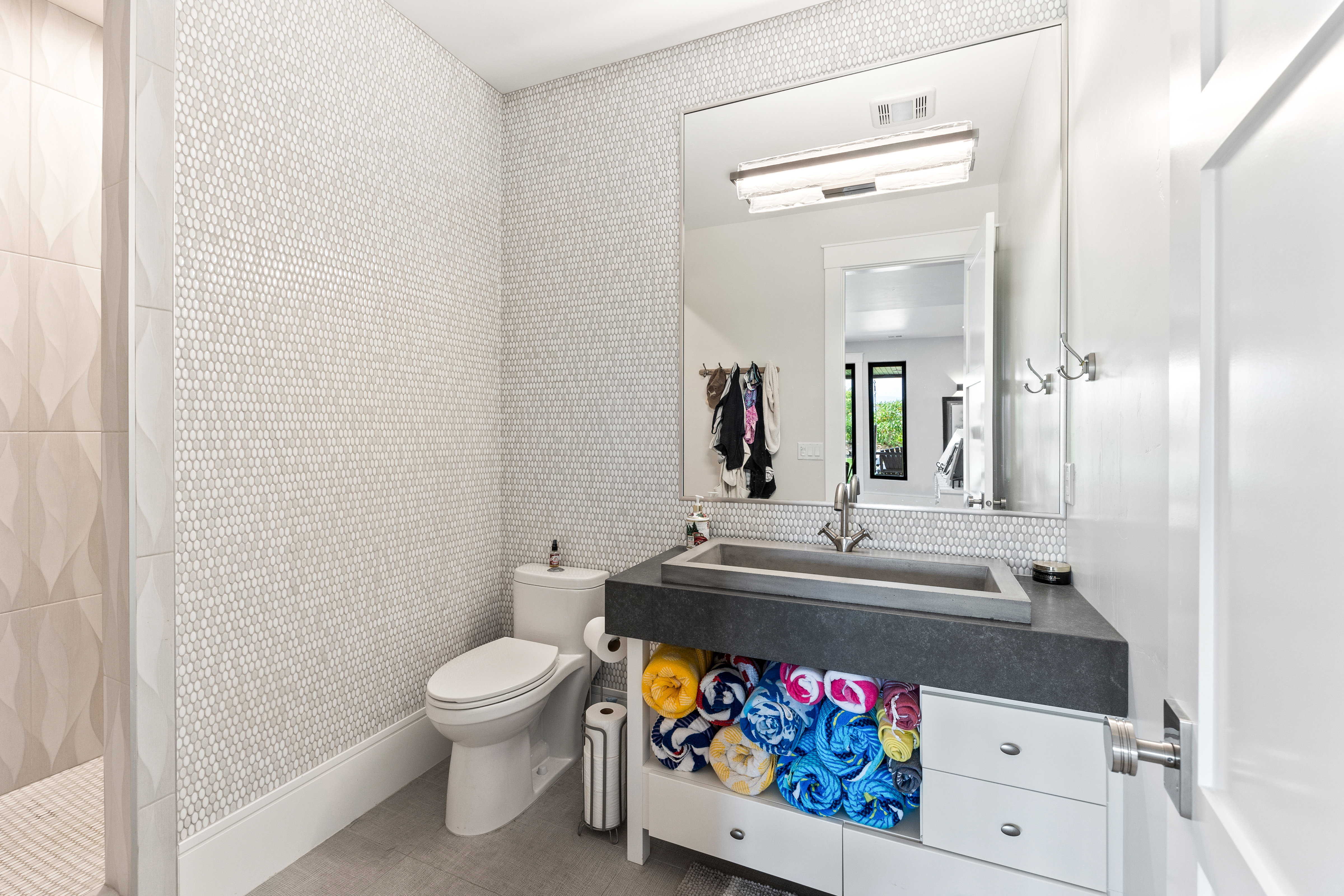 Full bathroom with a tile shower, wallpapered walls, and vanity