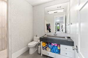 Full bathroom with a tile shower, wallpapered walls, and vanity