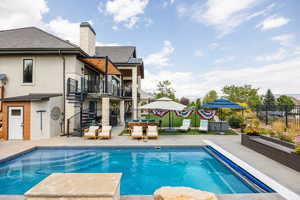 View of pool featuring stairway, a balcony, a patio, and outdoor dining area