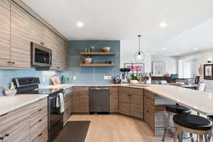 Kitchen featuring appliances with stainless steel finishes, a breakfast bar area, backsplash, a peninsula, and recessed lighting
