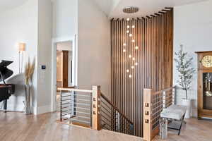 Hall with an upstairs landing, light wood-type flooring, and a high ceiling