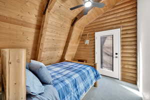 Carpeted bedroom featuring wooden ceiling, rustic walls, a ceiling fan, and vaulted ceiling