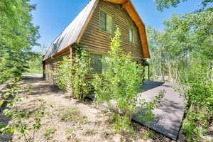 View of side of property with log siding, a metal roof, and a gambrel roof