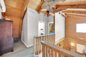 Corridor with wood ceiling, wood walls, an upstairs landing, carpet flooring, and log walls