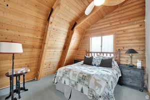 Bedroom with wooden ceiling, carpet floors, vaulted ceiling, and rustic walls