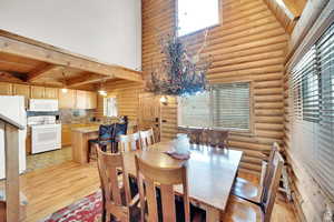 Dining space with a towering ceiling, light wood-style floors, rustic walls, and wooden ceiling