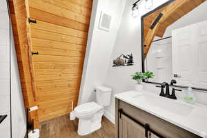 Full bathroom with vaulted ceiling, vanity, wooden ceiling, a shower with curtain, and wood finish floors
