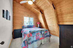 Bedroom featuring wooden ceiling, log walls, a ceiling fan, and carpet
