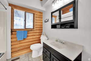 Bathroom featuring log walls, vanity, stone finish floors, and a shower