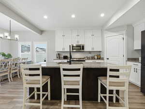 Kitchen featuring white cabinets, light stone countertops, recessed lighting, and light wood finished floors
