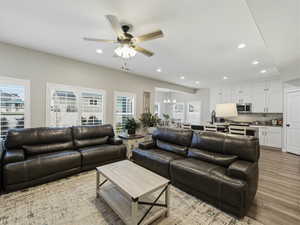 Living area with light wood-type flooring, recessed lighting, ceiling fan, and a chandelier