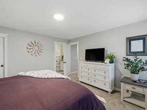 Bedroom with light carpet and ensuite bathroom