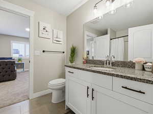 Bathroom featuring vanity, curtained shower, light colored carpet, and light tile patterned floors