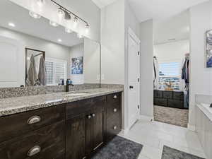 Full bath with vanity, a spacious closet, a stall shower, light tile patterned floors, and a tub