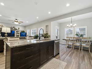 Kitchen featuring dark brown cabinets, light stone counters, light wood-style flooring, open floor plan, and recessed lighting