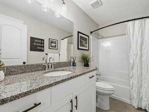 Bathroom with shower / bath combo, vanity, light tile patterned floors, and a textured ceiling