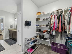 Spacious closet featuring dark carpet and dark tile patterned floors