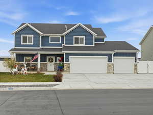Craftsman-style home featuring board and batten siding, stone siding, driveway, and roof with shingles