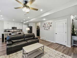 Living area with a ceiling fan, wood finished floors, washer / dryer, and recessed lighting