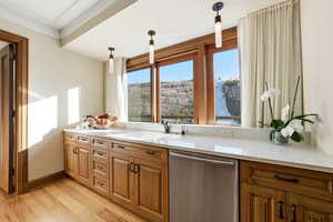 Kitchen with stainless steel dishwasher, brown cabinets, and hanging light fixtures