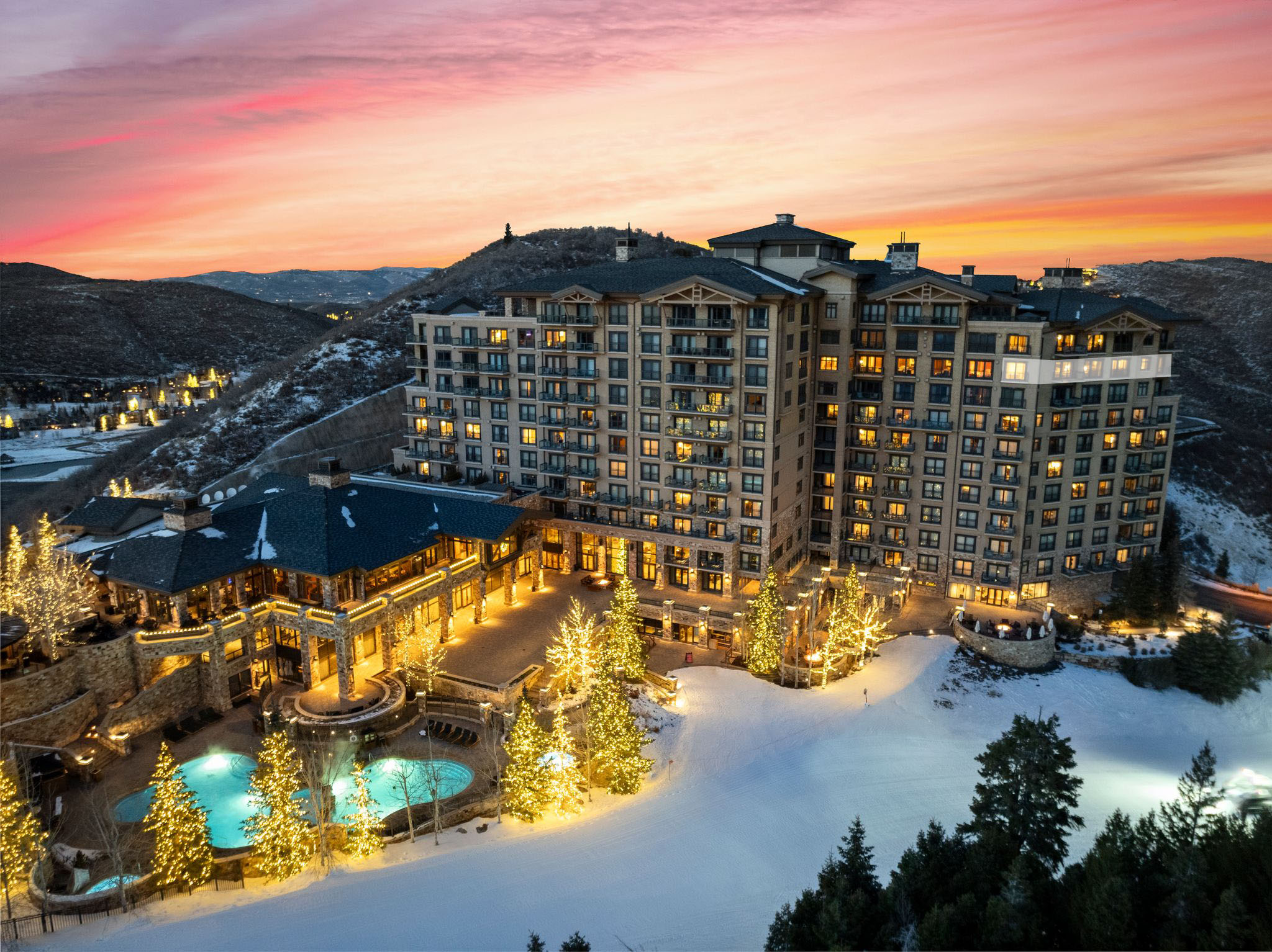 Snow covered building featuring a view of apartment building / complex, an outdoor pool, and a mountain view
