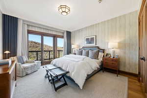 Bedroom featuring wallpapered walls, access to outside, and wood finished floors