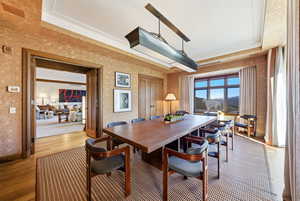 Dining space featuring light wood finished floors, a raised ceiling, and a textured wall