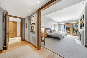 Bedroom with access to exterior, a fireplace with flush hearth, light wood-style flooring, and recessed lighting