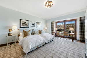 Bedroom featuring an office area, ornamental molding, and access to exterior