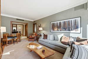 Living area with ornamental molding, wallpapered walls, and carpet