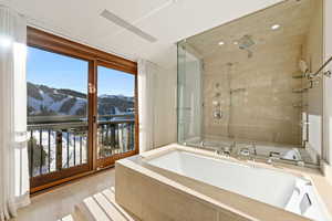 Bathroom with a bath, a stall shower, a mountain view, and light tile patterned floors