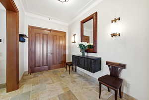 Foyer with stone tile floors and ornamental molding
