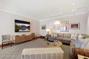 Living area with ornamental molding, light carpet, and recessed lighting