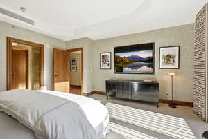 Bedroom with a tray ceiling, carpet, and wallpapered walls