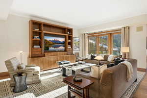 Living area with wood finished floors and ornamental molding