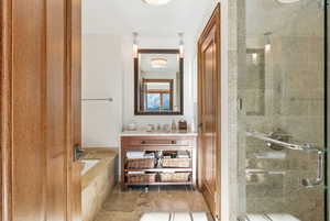Bathroom with vanity, a bath, and a stall shower