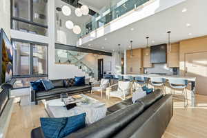 Living area with stairs, light wood-type flooring, and a towering ceiling