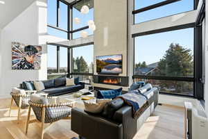 Living room with a large fireplace, a high ceiling, wood finished floors, and plenty of natural light