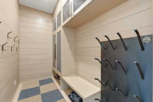 Mudroom featuring tile patterned floors and wood walls